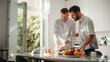 © Gorodenkoff - Stylish Young Adult Gay Couple at Home in Casual Clothes in Kitchen Area. Handsome Male Cutting Apples and Preparing Lunch. Partners Talking and have Fun. Cute LGBTQ Relationship Content.