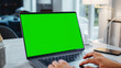 Green Screen Mock Up Display on a Laptop Computer. Close Up on Person's Hands Working from Modern Home, Using Touch Pad, Scrolling Content. Smartphone Lies Next to Computer.