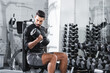 © LIGHTFIELD STUDIOS - Muslim sportsman looking at dumbbell while training in gym.