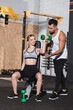 © LIGHTFIELD STUDIOS - Smiling young woman exercising with dumbbell near trainer in sports center.