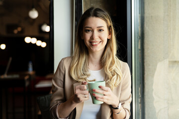 Canvas Print - Young businesswoman drinking coffee in her office.