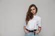 © alones - Pretty serious woman in white mockup t-shirt stands in studio on a gray background