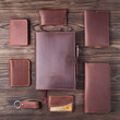 Set of handmade leather accessories on wooden background flat lay