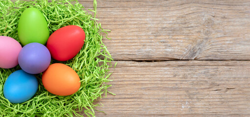 Easte pastel color egg in a nest on wood table background, overhead view