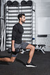 © LIGHTFIELD STUDIOS - Side view of muslim sportsman holding dumbbells while doing lunges in sports center.