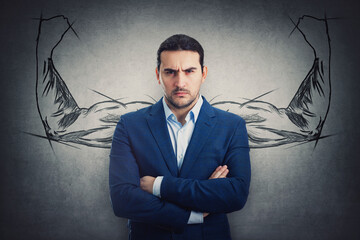 Portrait of businessman looking strained, isolated on grey wall with a sketch of muscular arms flexing biceps behind him. Angry person reacting annoyed. Business leadership concept