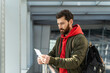 © NFstock - Waist up portrait of the young caucasian man standing at the airport lounge and checking his tickets. Traveling by the plane concept