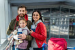 © NFstock - Portrait of the bearded father embracing his happy daughter while his wife standing nearby. Family waiting plane at the airport. Happy emotions concept
