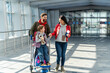 © NFstock - Father, mother and daughter getting ready for the flight while standing at departure lounge with suitcases and waiting for the aircraft arrival