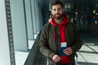 © NFstock - Waist up portrait view of the calm male tourist standing in airport and looking at the camera with happy expression. He is holding his passport and ticket