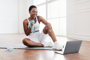 Wall Mural - Young black woman woman talking with online coach using pc