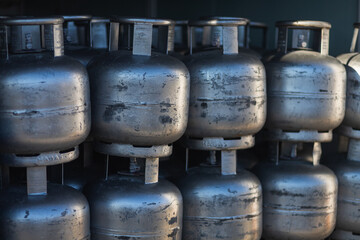 close-up of silvery gas cylinders stand on top of each other in even rows in a warehouse