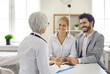 © Studio Romantic - Happy young married couple in hospital consults with experienced doctor about planning pregnancy. Portrait of expectant parents listening to advice of female gynecologist. Health and pregnancy concept