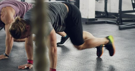 Wall Mural - Fitness in sync. Fitness group of active young people doing a workout together at a gym. Line of people at a health club doing mountain climbers during exercise. Health, wellness and sport concept