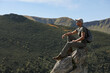 © New Africa - Tourist with backpack enjoying mountain landscape on rocky peak