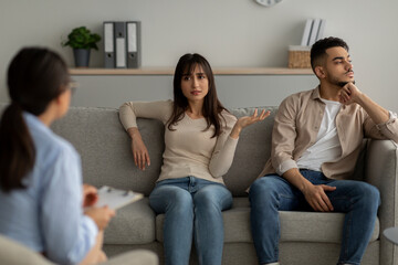 Wall Mural - Family conflicts. Arab spouses having quarrel, blaming each other for unhappy life, sitting at psychologist appointment