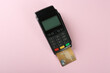 © New Africa - New modern payment terminal with credit card on pink background, top view