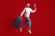 © Prostock-studio - Excited Young Man In Santa Hat Jumping With American Flag And Suitcase