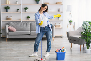 Wall Mural - Portrait of excited woman cleaning floor singing holding mop