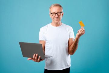 Wall Mural - Excited mature man holding credit card and laptop