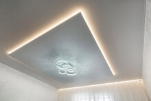 Suspended Ceiling With Halogen Spots Lamps And Drywall Construction In Empty Room In Apartment Or House. Stretch Ceiling White And Complex Shape.