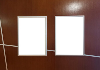 White template for two paintings, posters or photographs in an aluminum frame hung on a brown wooden wall, copy space