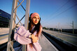 © chika_milan - A teenage girl is leaning on the metal construction at the train station and enjoying the music.