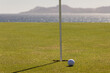 Tee box and golf ball close-up on tropical seaside golf course in late day sun. Copy space.
