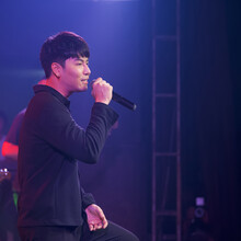 Young Black-haired Asian Singer With A Microphone Singing On Stage. The Atmosphere At Night In The Pub