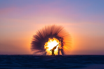 Woman on a frozen lake at sunrise. in arctic Canada. Girl splashes boiling water on cold air which instantly turns to snow, steam in freezing temperatures. 