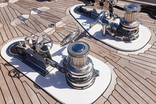 Teak Deck Of A Luxury Yacht With Stainless Steel Winches And Anchor Chain Attachment Mechanisms.