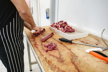 Poster - Butcher cutting slices of raw meat on wooden board