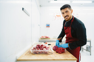 Poster - Butcher cutting slices of raw meat on wooden board