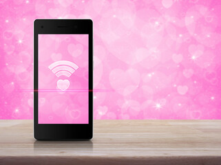 Heart love wifi flat icon on modern smart mobile phone screen on wooden table over blur pink wall, Internet love online, Valentines day concept