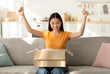 © Prostock-studio - Delivery service. Overjoyed asian lady unpacking parcel box clenching fists, happy about receiving package