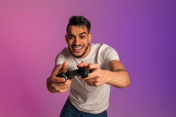 Poster - Handsome young Arab man using joystick, playing online video game in neon light