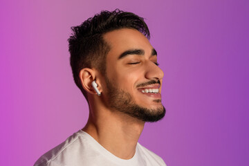 Poster - Handsome young Arab guy in casual outfit listening to music in earphones, closing eyes and relaxing in neon light