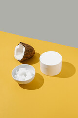 Half a coconut, coconut oil and a jar of coconut cream on a yellow background.