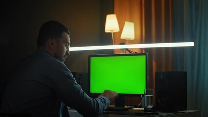 The young male working at home office hands on keyboard. The screen is a green background.