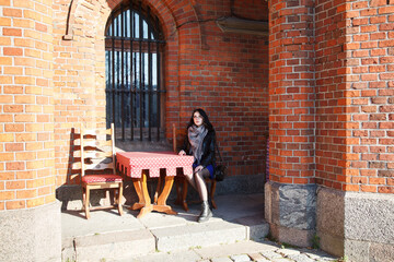 Wall Mural - young girl sits at table in street cafe on autumn day