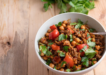 Wall Mural - Ground beef with chick peas and vegetables in a bowl isolated on wooden table from above