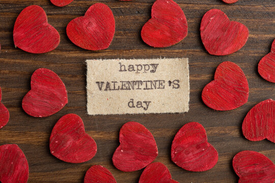 Happy Valentine`s day - typed text. Valentines Day greetings concept. Little red wooden hearts close up. Valentines greeting card.