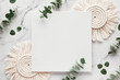 Mockup with blank square canvas, copy-space. Eucalyptus twigs, macrame pads.Winter flat lay background . Top view on white marble