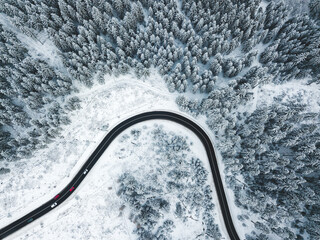 Sticker - Aerial photo of a curvy road going trough the snowy forest.