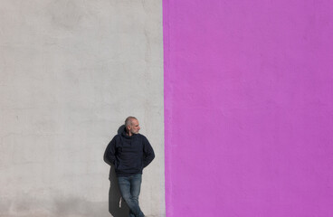 Adult man standing against white and purple wall