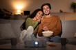 © Prostock-studio - Husband And Wife Laughing Watching Movie Via Projector At Home