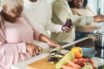 Wall Mural - Happy black family cooking inside kitchen at home - Focus on left hand holding knife