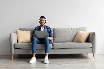 Aufkleber - Smiling Arab man in headphones using pc at home