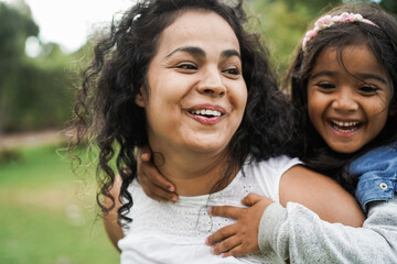 Wall Mural - happy indian mother having fun with her daughter outdoor - soft focus on mom face