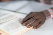 © Svyatoslav Lypynskyy - Close up african american man hand on a open book. Student preparing to the lecture at library reading books and making notes. Adduction concept